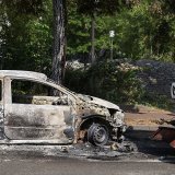 Un employé municipal nettoie la rue près d'une voiture incendiée mercredià Nanterre.